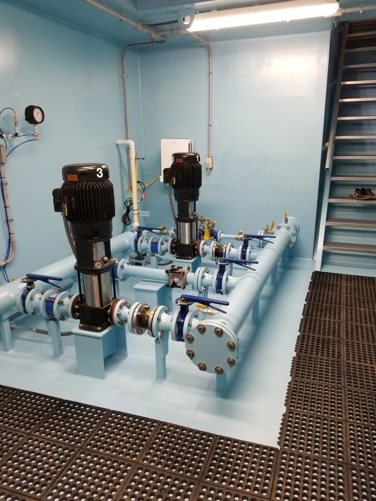Below-grade water booster vault interior with vertical pumps and access stairs