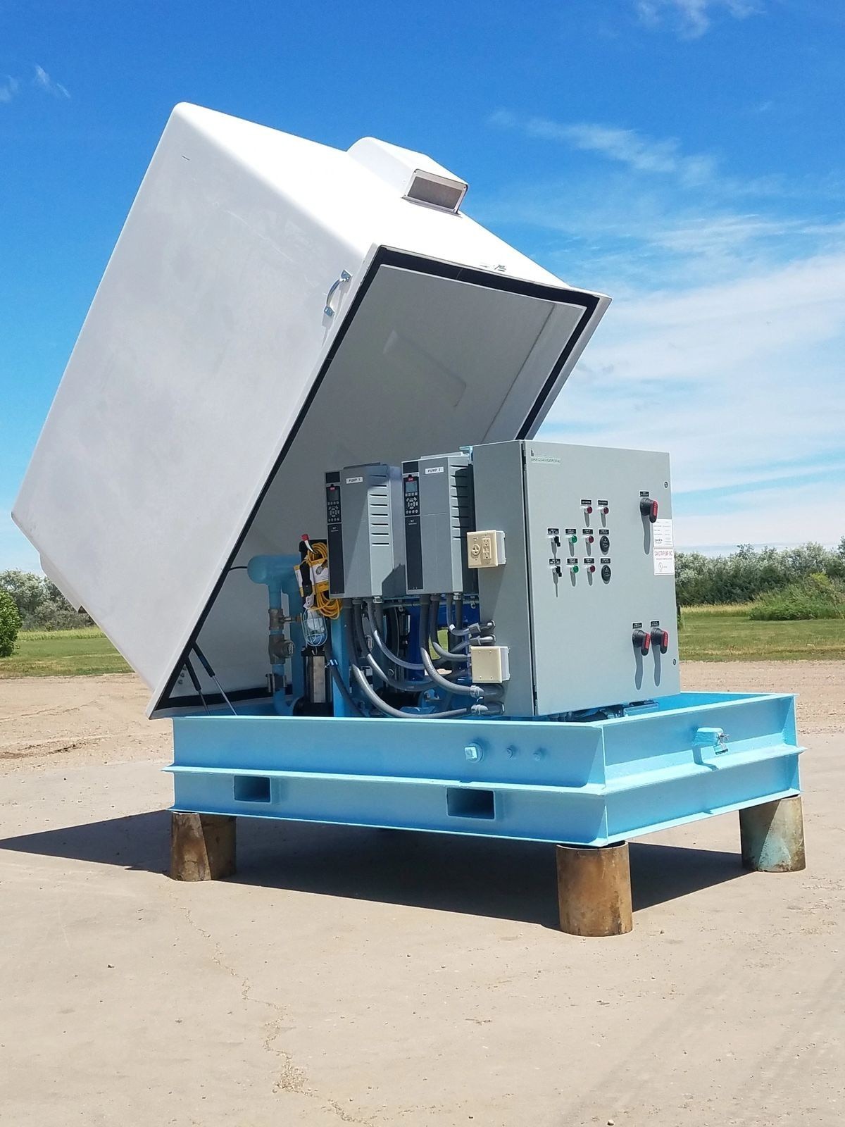 Grade-mounted packaged water booster station with hinged enclosure and controls